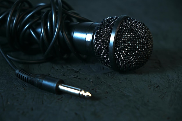 Czarny mikrofon upadł na czarną drewnianą podłogę. Instrument muzyczny do śpiewania i karaoke.