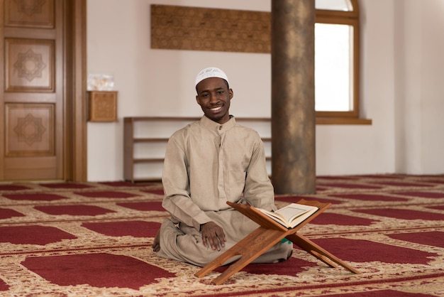 Czarny muzułmanin z Afryki czyta świętą islamską księgę Koran