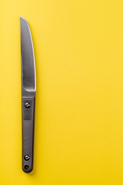 Czarny nóż na żółtym tle koncepcji survivalu i bushcraftu