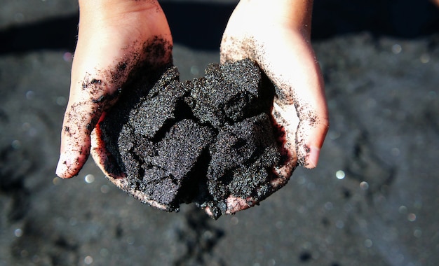 Zdjęcie czarny piasek wulkaniczny w rękach dziecka, lanzarote, wyspa