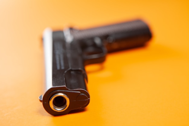 Zdjęcie czarny pistolet na pomarańczowej powierzchni.