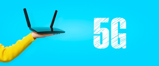 Czarny router wifi pod ręką na żółtej ścianie, koncepcja 5G