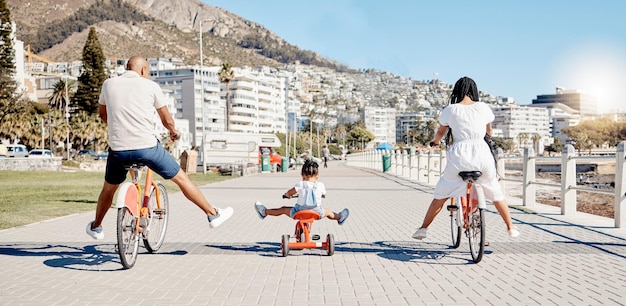 Czarny rower rodzinny i dzieci z dziewczynką i rodzicami bawiące się razem na promenadzie latem Rower Freedom i dzieci z matką, ojcem i córką jadącymi podczas łączenia z tyłu