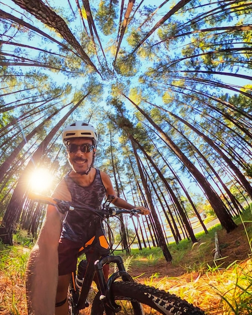 Zdjęcie czarny rowerzysta na leśnym szlaku robi selfie na rowerze w słoneczny dzień obraz koncepcyjny