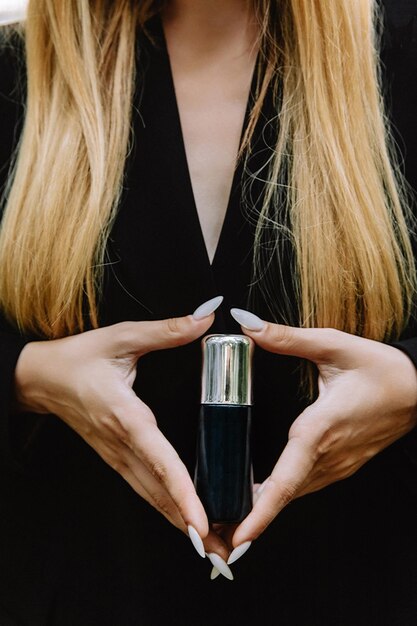 Zdjęcie czarny słoik ze srebrną pokrywką kosmetyki w sprayu w rękach dziewczyny na tle ciała