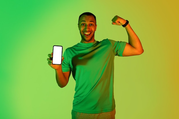Czarny Sportowiec Wyświetlono Pusty Ekran Telefonu I Biceps Zielone Tło