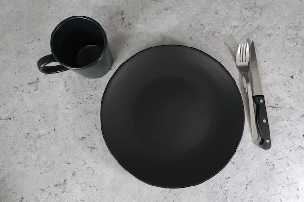 Czarny talerz i czarny kubek na szarym stole