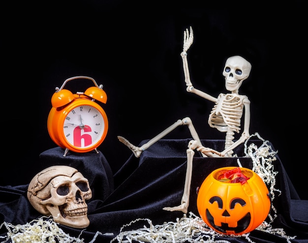 Czas Halloween Zabawka Szkielet wyczołgujący się z grobu i machający ręką wita dynie grymasami Pomarańczowy zegar Czaszka na czarnym tle Wigilia dnia śmierci