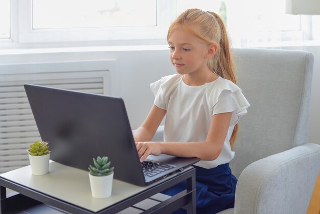 Czas nauki Zainteresowana mała uczennica siedzi i ogląda edukacyjną lekcję wideo