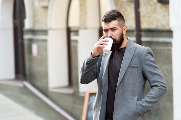Czas się napić. Brodaty mężczyzna pije poranną kawę. Hipster z jednorazowym papierowym kubkiem spaceru po mieście. Biznesmen w stylu hipster trzymając kawę na wynos. Najlepsza pora dnia na kawę.