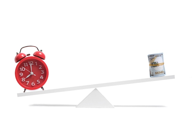 Zdjęcie czas w postaci czerwonego budzika na wadze przeważa banknoty dolarowe, koncepcja czas to pieniądz.