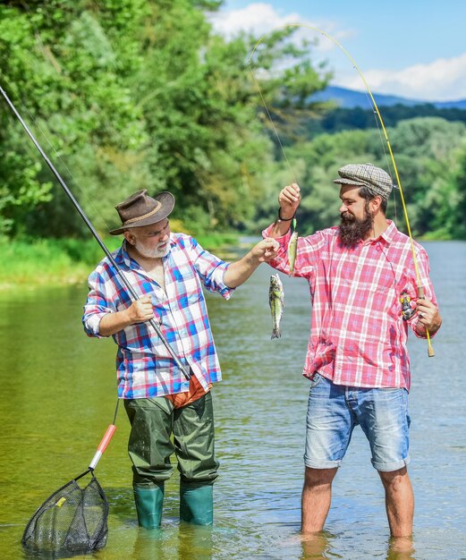 Czas zjazdu rodzinnego ojciec i syn wędkowanie przyjaźń męska więź rodzinna letni weekend dwóch rybaków z wędkami przynęta na pstrągi dojrzali mężczyźni rybak hobby i sport