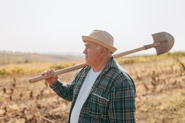 Czas żniwa doświadczony rolnik niosący łopatę gotowy dbać o swoje obfite pola stały w