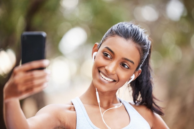 Czas zrobić kilka zdjęć w mediach społecznościowych Ujęcie młodej kobiety używającej smartfona do robienia selfie podczas codziennego joggingu