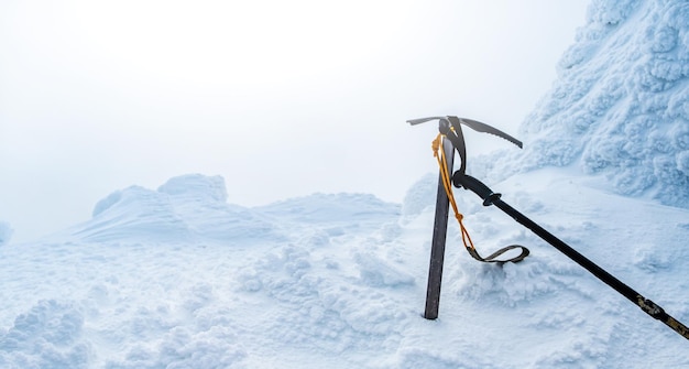 Czekan i kij trekkingowy otoczone śniegiem