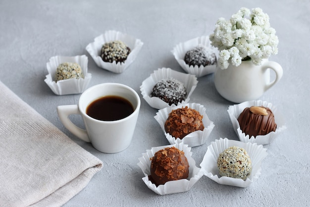 Zdjęcie czekoladowe cukierki, filiżanka kawy i bukiet kwiatów na walentynki na szarym stole.