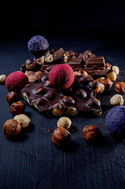 Czekoladowe cukierki trufla z kawałkami czekolady i latającym kakao w proszku na ciemnym tle.