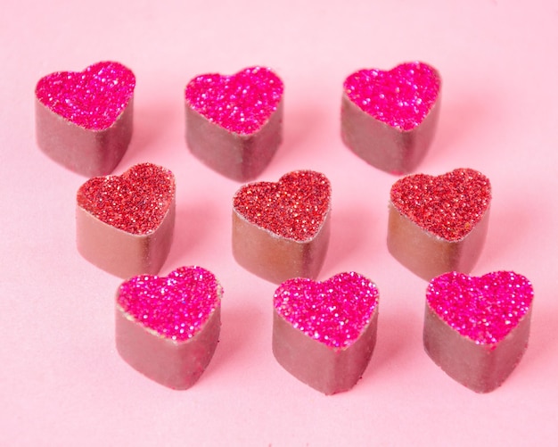 Zdjęcie czekoladowe cukierki w kształcie różowych serc różowe gładkie tło