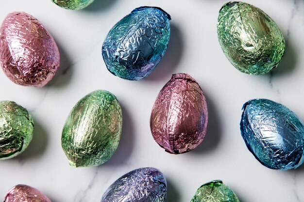 Czekoladowe Jajka Wielkanocne Zawijane W Błyszczącą Kolorową Folię Na Marmurowym Tle