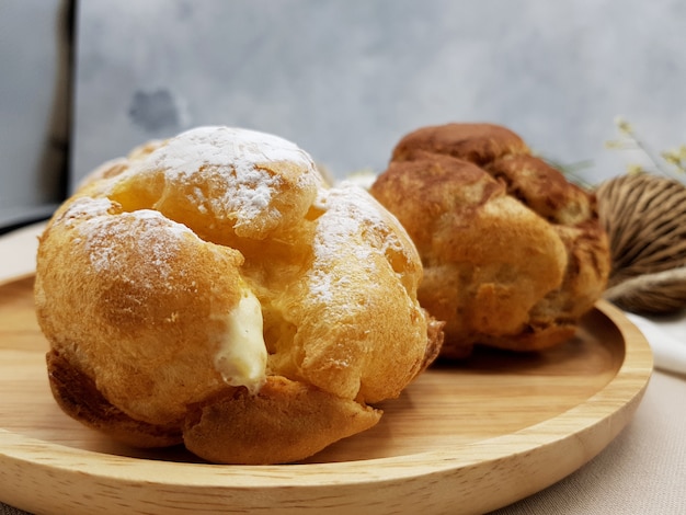 Zdjęcie czekoladowi i waniliowi choux kremowy chuch na drewnianym talerzu