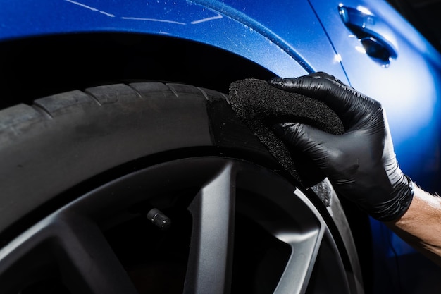 Czernienie felgi samochodu gąbką z chemicznym czernieniem gumy w serwisie detailingowym