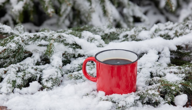 Czerwona filiżanka kawy i śniegu wokół na drewnianym stole w zamieci