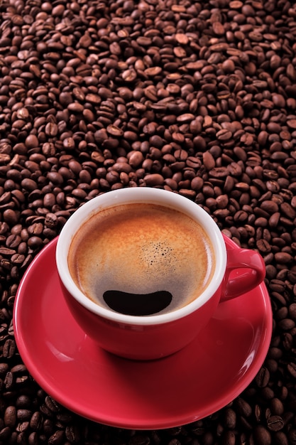 Czerwona filiżanka z kawą espresso i piec fasolami pionowo