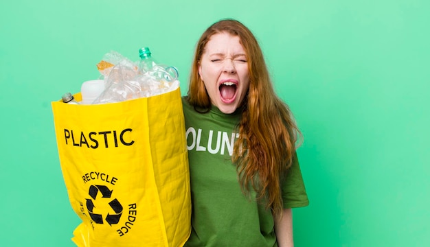 Czerwona głowa ładna kobieta krzyczy agresywnie, wyglądając na bardzo złą koncepcję recyklingu