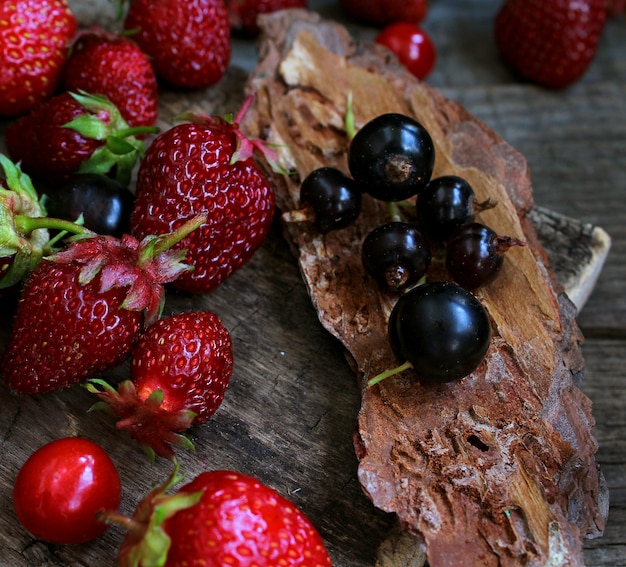 Czerwona jagodowa truskawka, drewniany nieociosany tło. Organiczne produkty naturalne.