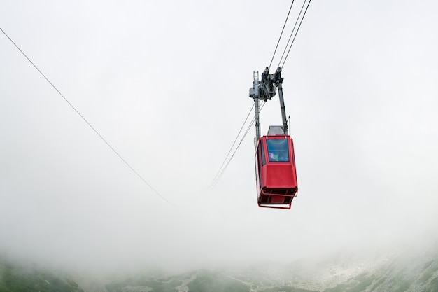 Czerwona kolejka linowa lub czerwona podwieszana kolejka linowa na Łomnicki szczyt we mgle lub chmurach wysoka tatry słowacja