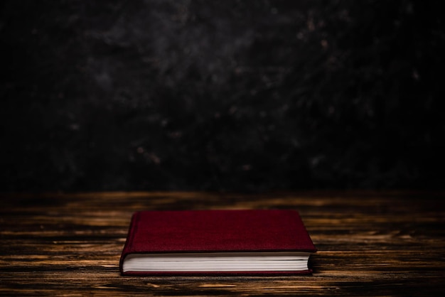 Czerwona książka na drewnianym stole na czarnym tle