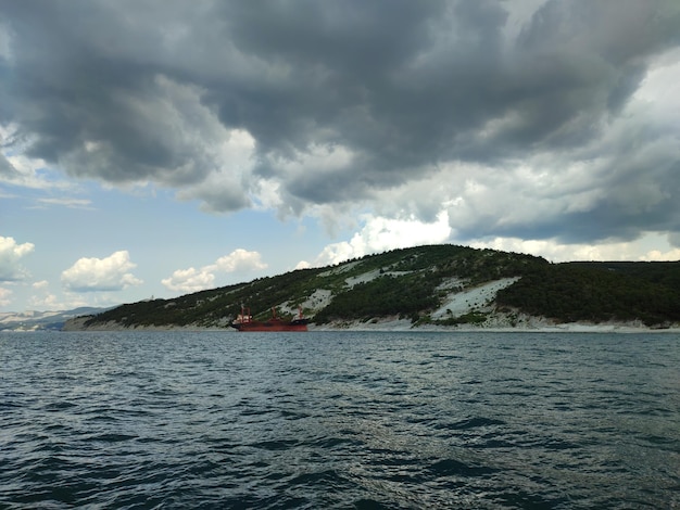 Czerwona łódź płynie po wodzie w pobliżu góry.
