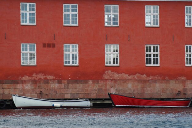 Zdjęcie czerwona łódź zacumowana na kanale przed budynkiem w mieście