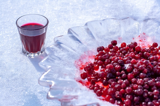 Czerwona Nalewka Alkoholowa W Małej Szklance I żurawina W Lodowym Talerzu. Alkohol W Szklance Stoi Na śniegu. Skoncentruj Się Na Szkle. Poziomy.