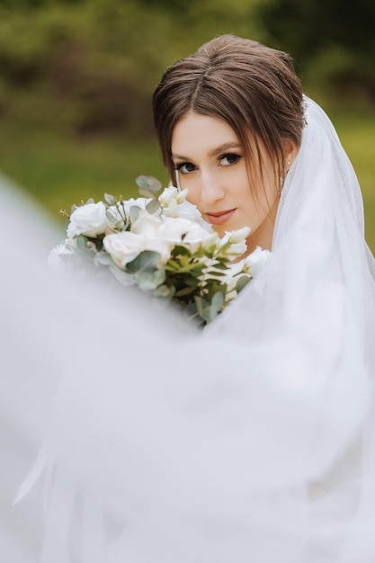 Czerwona panna młoda pozuje na tle kwitnącego drzewa Wspaniała suknia z długimi rękawami otwarty popiersie Wiosenne wesele
