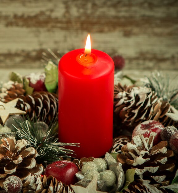 Czerwona świeca świeci i szyszki na Boże Narodzenie