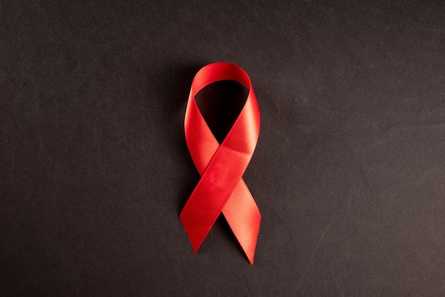 Czerwona wstążka HIV, AIDS na czarnym tle, świadomość, znak medyczny. miejsce na kopię.