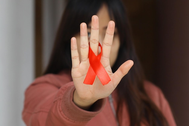 Czerwona wstążka na symbolu dłoni kobiety świadomości HIV i AIDS