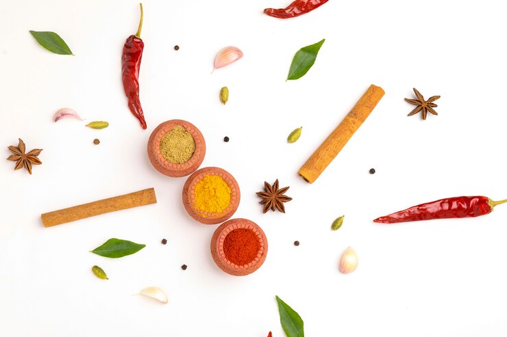 Zdjęcie czerwone chili w proszku, kurkuma w proszku i kolendra w proszku w glinianej misce z innymi przyprawami.
