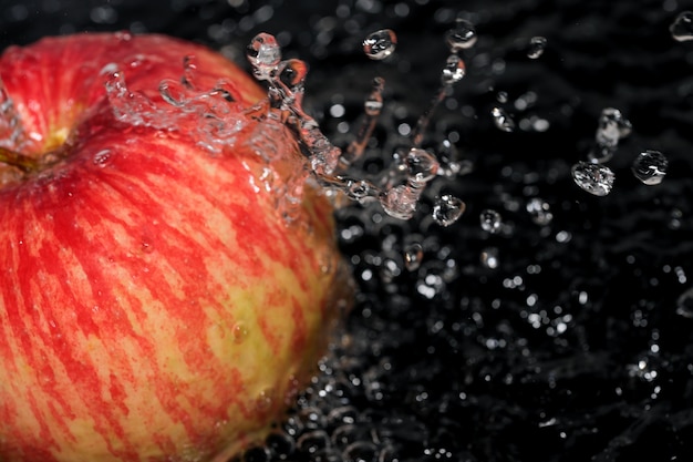 Czerwone dojrzałe słodkie jabłko pod strumieniem czystej wody makrofotografii z bliska