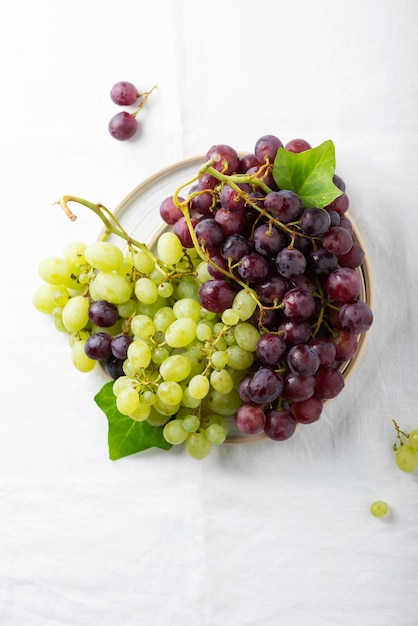 Czerwone i żółte winogrona na białym lnianym obrusie