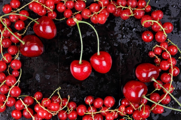 Czerwone jagody z kropli wody na czarnym tle Widok z góry Koncepcja zdrowej żywności