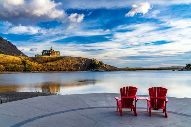 Czerwone krzesło patrzeć na Waterton Lake Marina Point w jesienny sezon liści w słoneczny poranek. Park Narodowy Waterton Lakes, Alberta, Kanada.