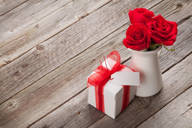 Czerwone kwiaty róży w dzbanku i pudełku prezentowym