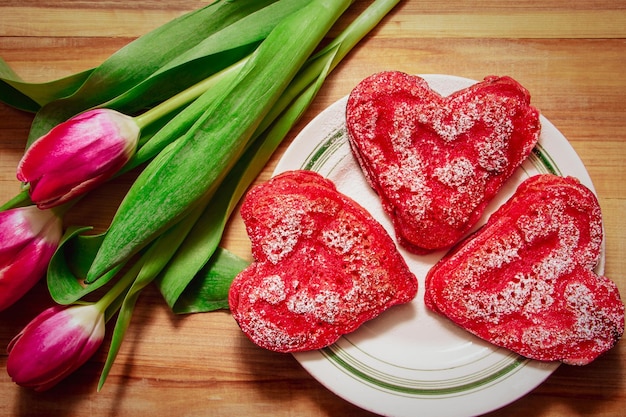 Zdjęcie czerwone naleśniki w kształcie serca wykonane z miłości do walentynek i tulipanów na drewnianym tle