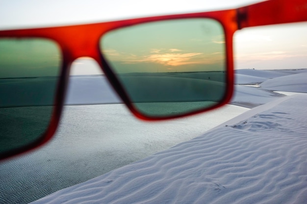 czerwone okulary przeciwsłoneczne filtrujące światło słoneczne na wydmach parku narodowego Lencois Maranhenses w Brazylii