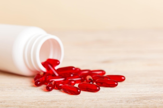 Czerwone pigułki rozlane wokół butelki pigułki Leki i pigułki na receptę płaskie świecące tło Czerwone kapsułki medyczne
