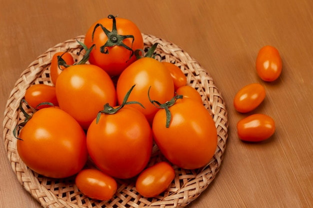 Czerwone pomidory na wiklinowym talerzu Brązowe tło