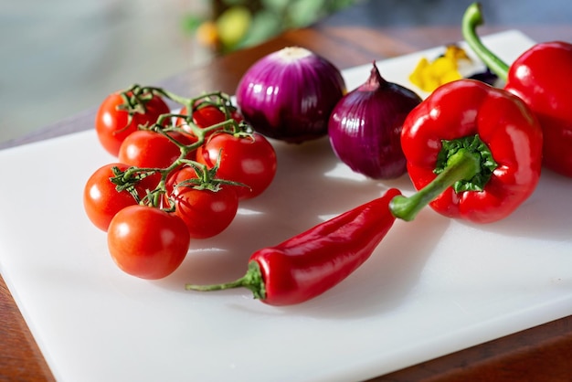 Czerwone pomidory, papryka, papryka chili i zielona cebula organiczne warzywa na desce do gotowania Zdrowa żywność wegetariańska Odżywianie Miękkie selektywne skupienie