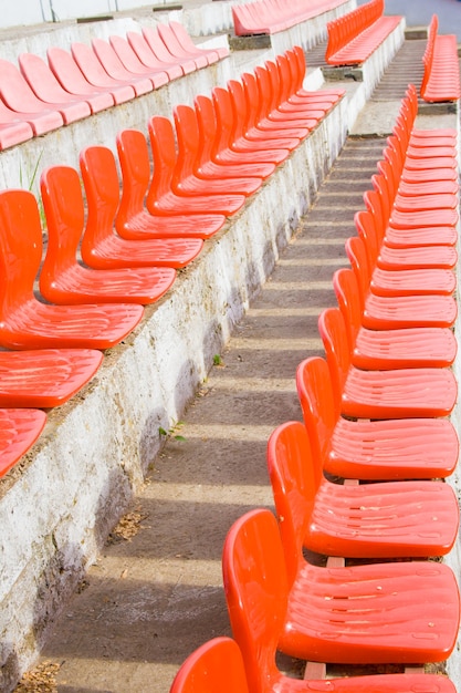 Czerwone puste plastikowe siedzenia małego stadionu. Pionowe tło